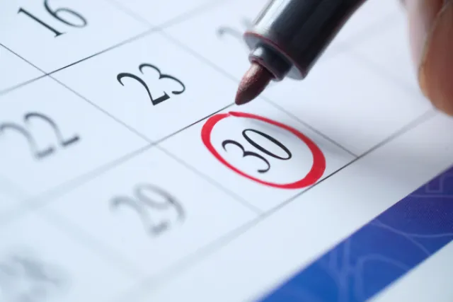 A red pen rings the day 30 on a calendar